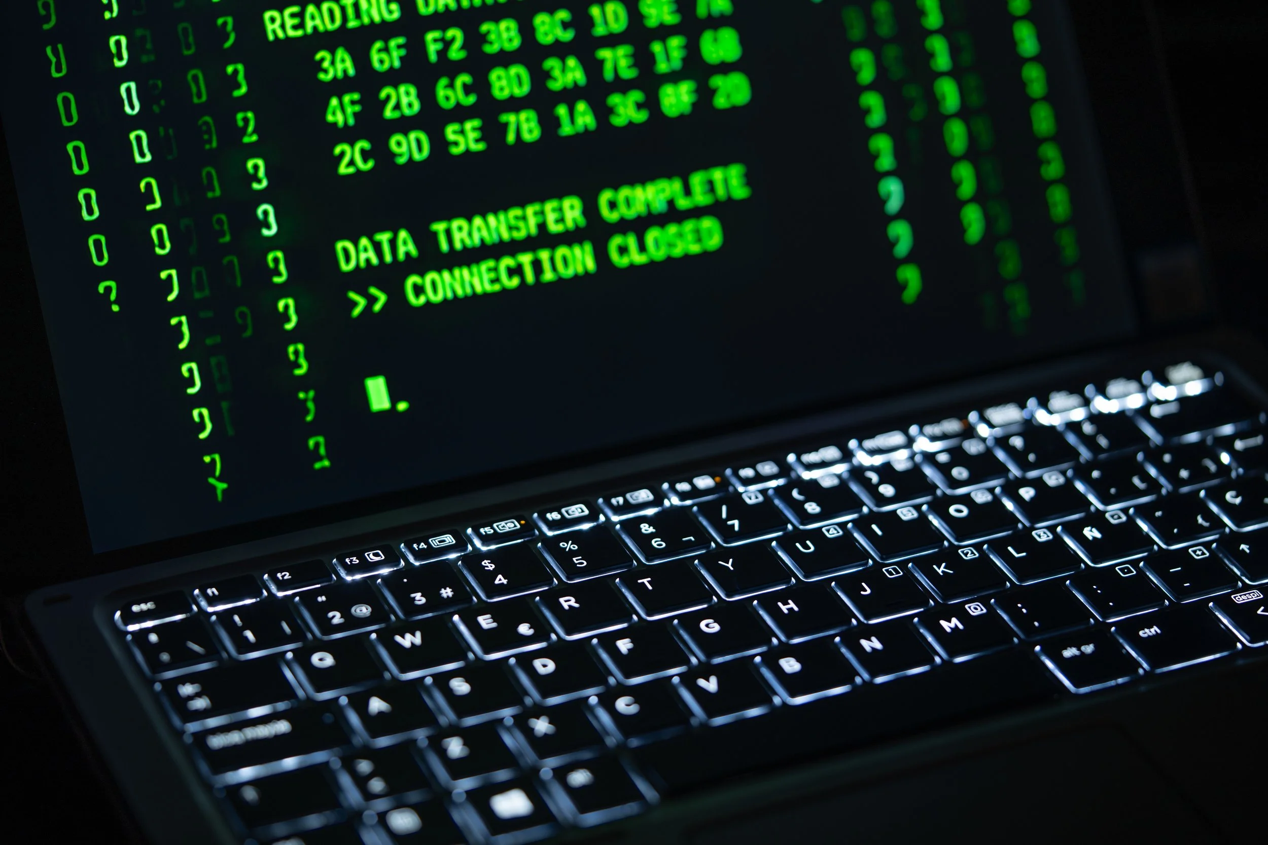 Laptop screen filled with green code ending in the lines DATA TRANSFER COMPLETE and CONNECTION CLOSED